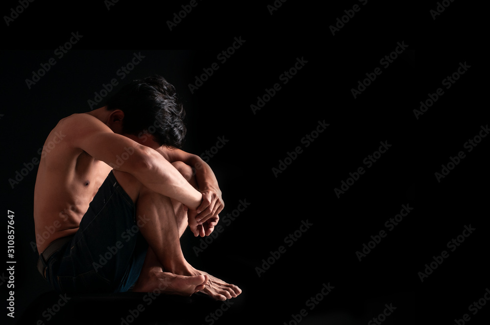 Sad man hug her knee with depression sitting alone on the floor in the dark room, Black and white photo Sad man hug her knee with depression sitting alone on the floor in the dark room, Black and white photo