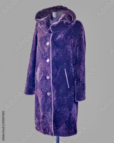 Long fur coat made of mouton, cut in rhombuses, with a hood and ikos pockets of dark violet color for the catalog photo