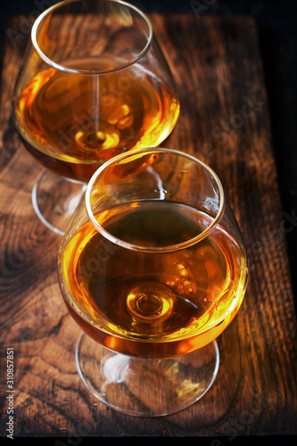 Two glasses of brandy or cognac on dark table
