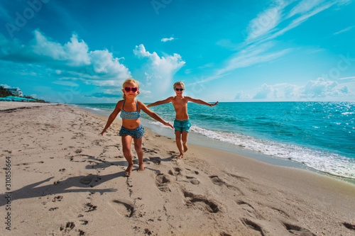 cute happy girl and boy running on beach