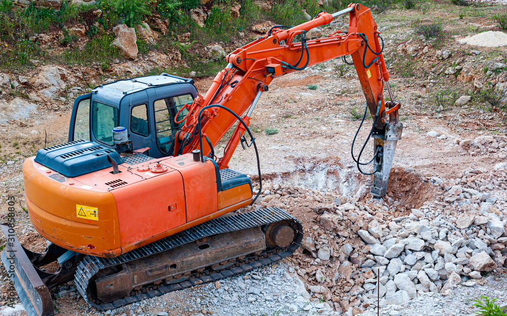 Hydraulic hammer works in a quarry against the background of huge stones Hydraulic hammer works in a quarry against the background of huge stones