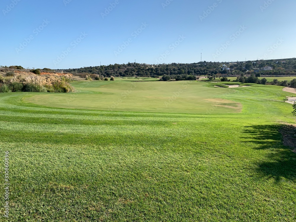 wide golf fairway with clear blue sky and