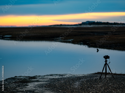 A Film Camera On a Tripod Sits Alone on the Bank of a River