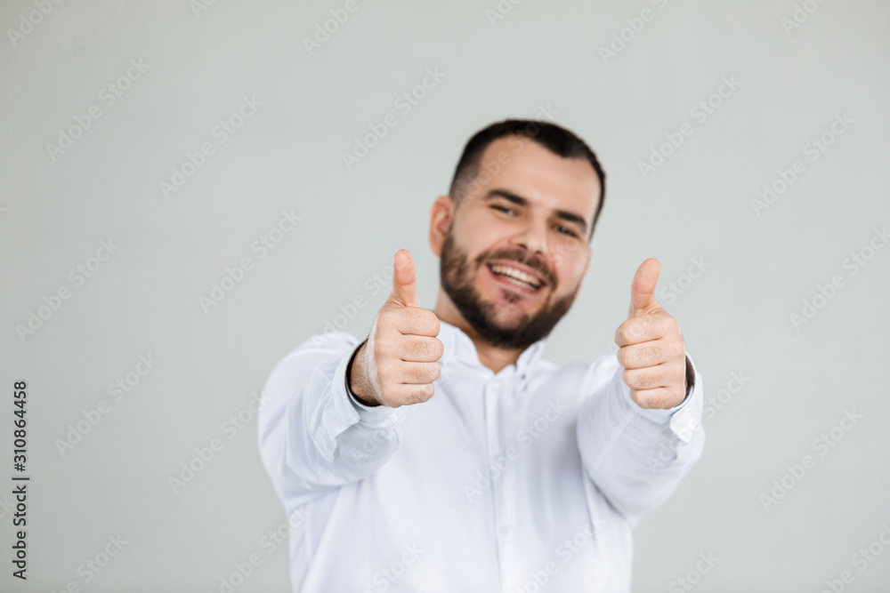 portrait of happy bearded man showing thumbs up on gray background. portrait of happy bearded man showing thumbs up on gray background.