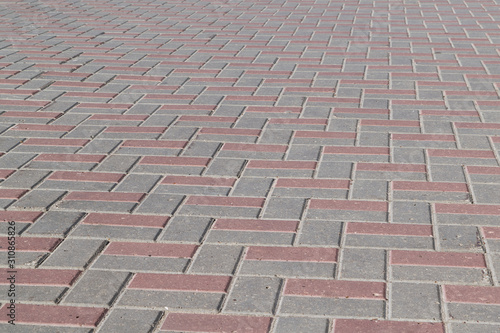 The surface of the pavement paved with paving stones of rectangular shape. The pavers are lined with a pattern. Tiles are gray and brown. Background or backdrop.