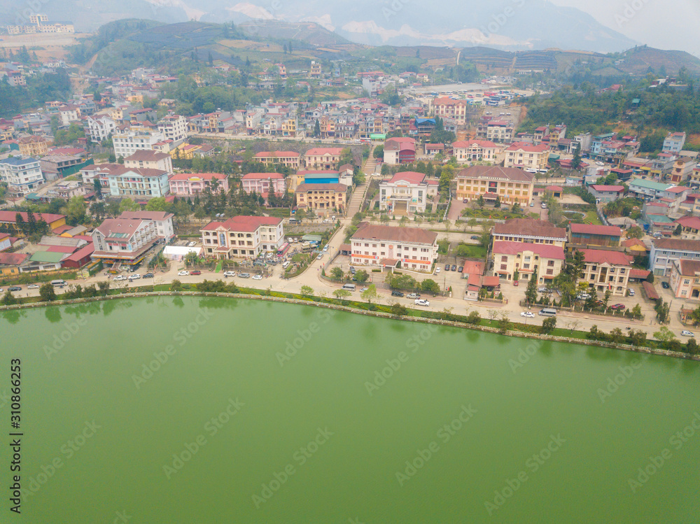 Aerial view of Sapa cityscape covered by fog with Sapa lake an iconic emerald green lake in the downtown of Sapa the capital city in Lao Cai province in north-west of Vietnam.