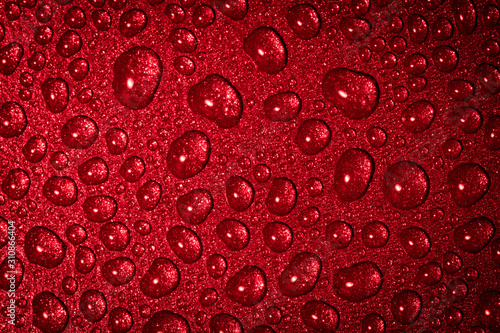 A close up abstract macro photo of water droplets on a grey non stick frying pan material lit with a red flash gel