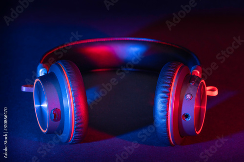 A pair of generic headphones made of brushed metal with a leather headband lit with a red and blue flash gels