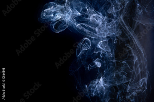 A close up macro photo of incense smoke lit by a blue flash to create a moody glow overlay with copy space