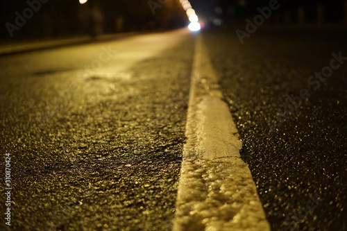 Separation line on the asphalt. Night road. Macro view.
