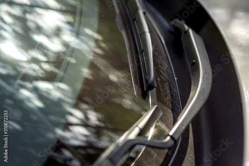 Dirty car windshield wipers with dry mud on front window close up.