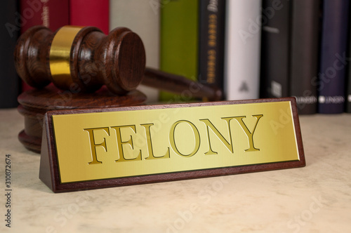 Golden sign with gavel and engraved word felony on a desk