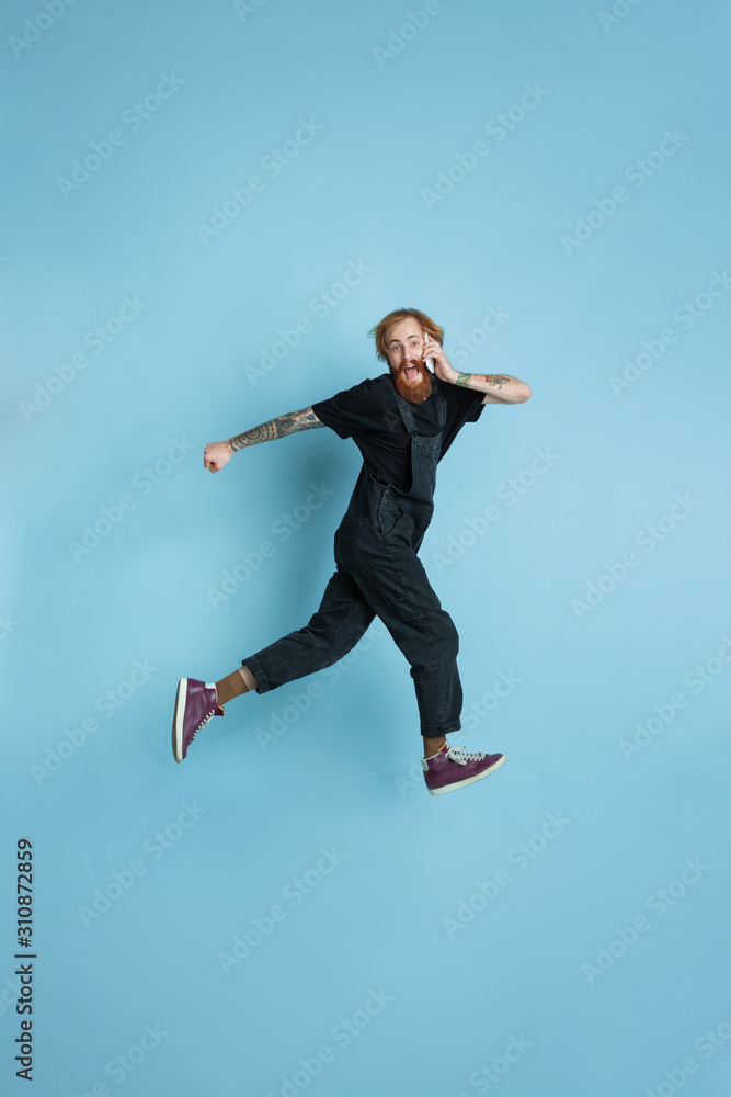 Portrait of young caucasian man looks dreamful, cute and happy. Jumping. laughting on blue studio background. Copyspace for your advertising. Concept of future, target, dreams, visualisation. Portrait of young caucasian man looks dreamful, cute and happy. Jumping. laughting on blue studio background. Copyspace for your advertising. Concept of future, target, dreams, visualisation.