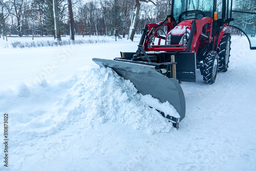 snow removal by tractor from a pedestrian road in a park in winter