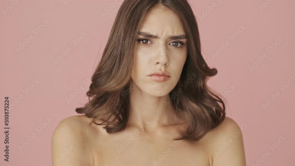 A serious pretty half-naked woman is shaking her head negatively isolated over pink background A serious pretty half-naked woman is shaking her head negatively isolated over pink background