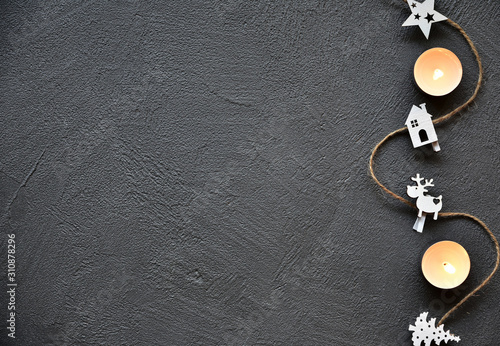 Wooden Christmas decoration and candles on a dark stone background. Festive background.