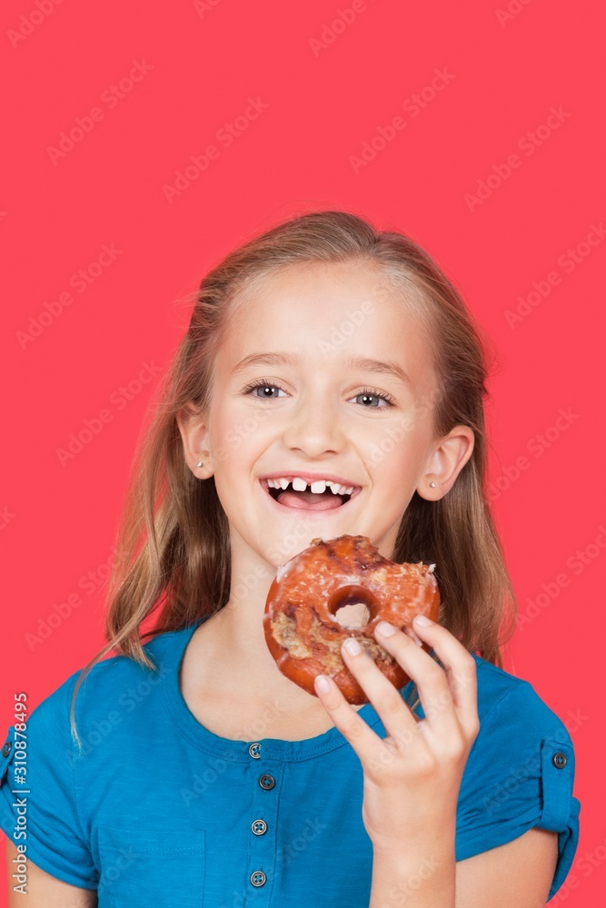 Portrait of happy young girl holding donut against red background Portrait of happy young girl holding donut against red background