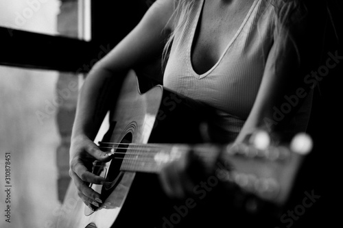 girl plays the guitar near the window in a white T-shirt black and white