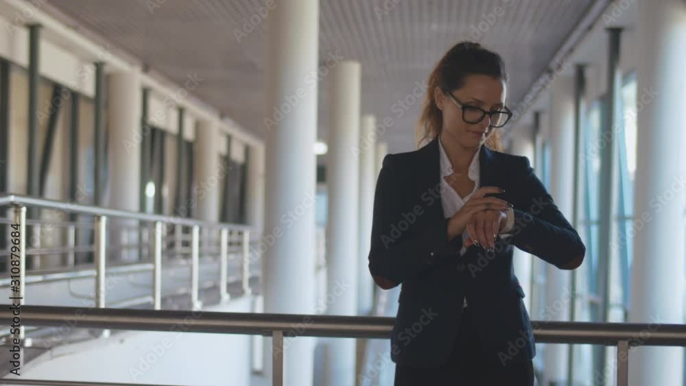 Portrait of young business lady adjusting her smartwatch in office hall. Portrait of young business lady adjusting her smartwatch in office hall.