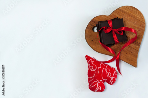 The Concept Of Valentine's Day. The border is made of chocolate bars, red ribbons, a heart-shaped cutting Board and a handmade decorative textile heart. Free space for your text. © Valentina