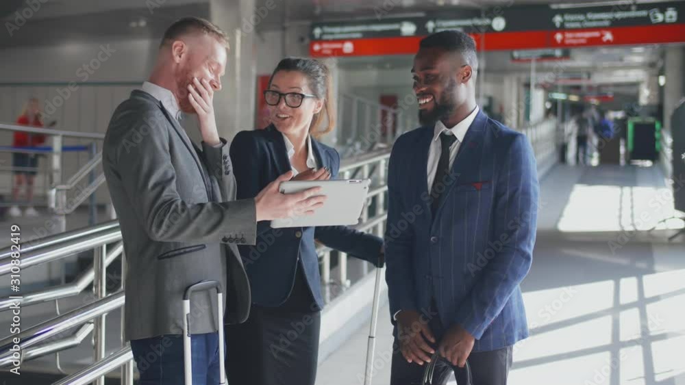 Three businesspeople using tablet computer while planning business trip in airport terminal Three businesspeople using tablet computer while planning business trip in airport terminal