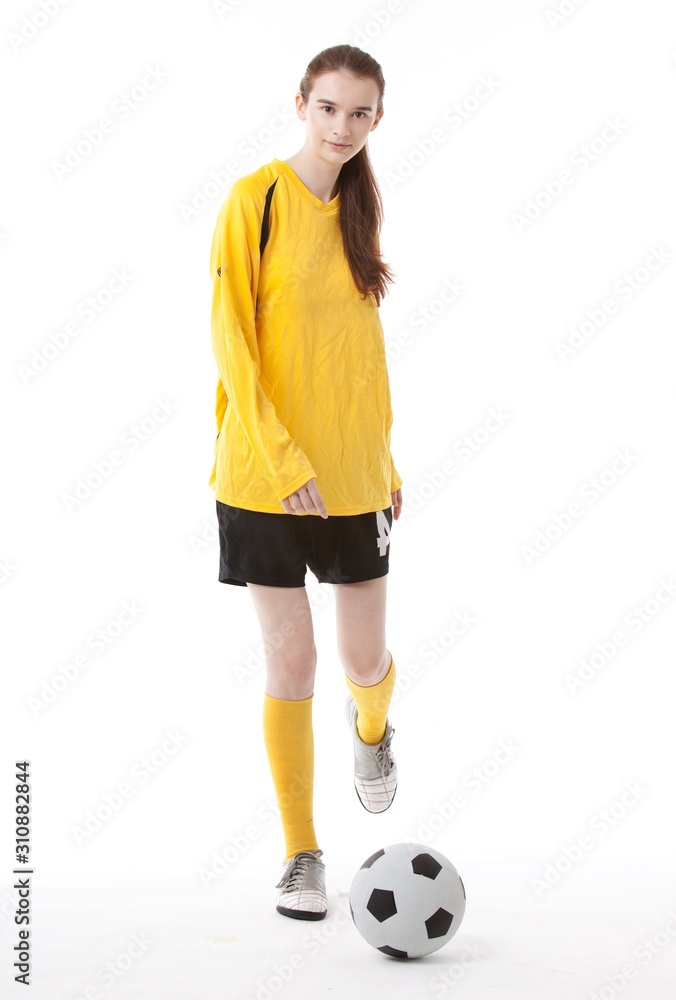Portrait of young female soccer player kicking the ball against white background