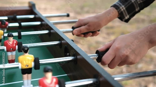 Friends play table football, or kicker. A close-up of the player's hands and players.