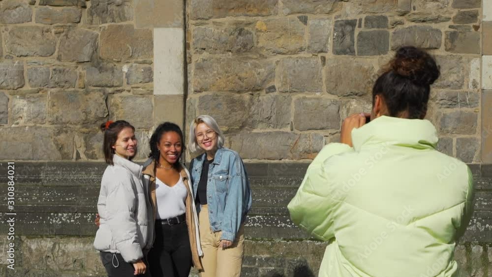 Four Young Multiracial Teen Girls Taking Photos by Smartphone on a Street. Ancient German Building is on the Background. People, Friendship, Communication and Lifestyle concept Four Young Multiracial Teen Girls Taking Photos by Smartphone on a Street. Ancient German Building is on the Background. People, Friendship, Communication and Lifestyle concept