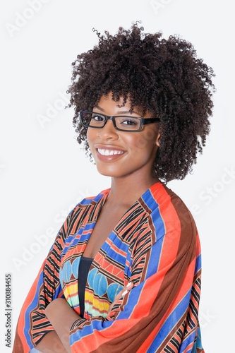 Portrait of young woman in African print attire standing hands folded over gray background