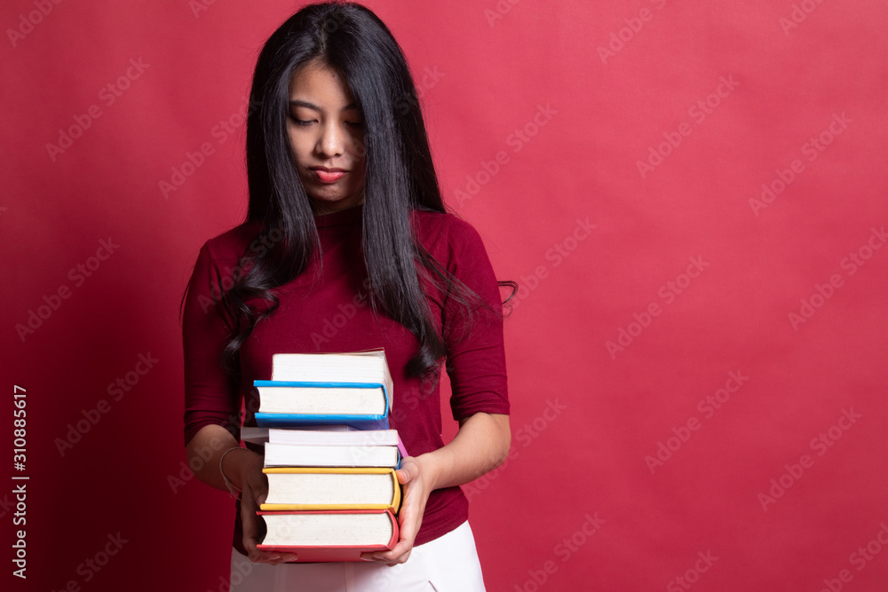 Unhappy young Asian woman studying with may books. Unhappy young Asian woman studying with may books.