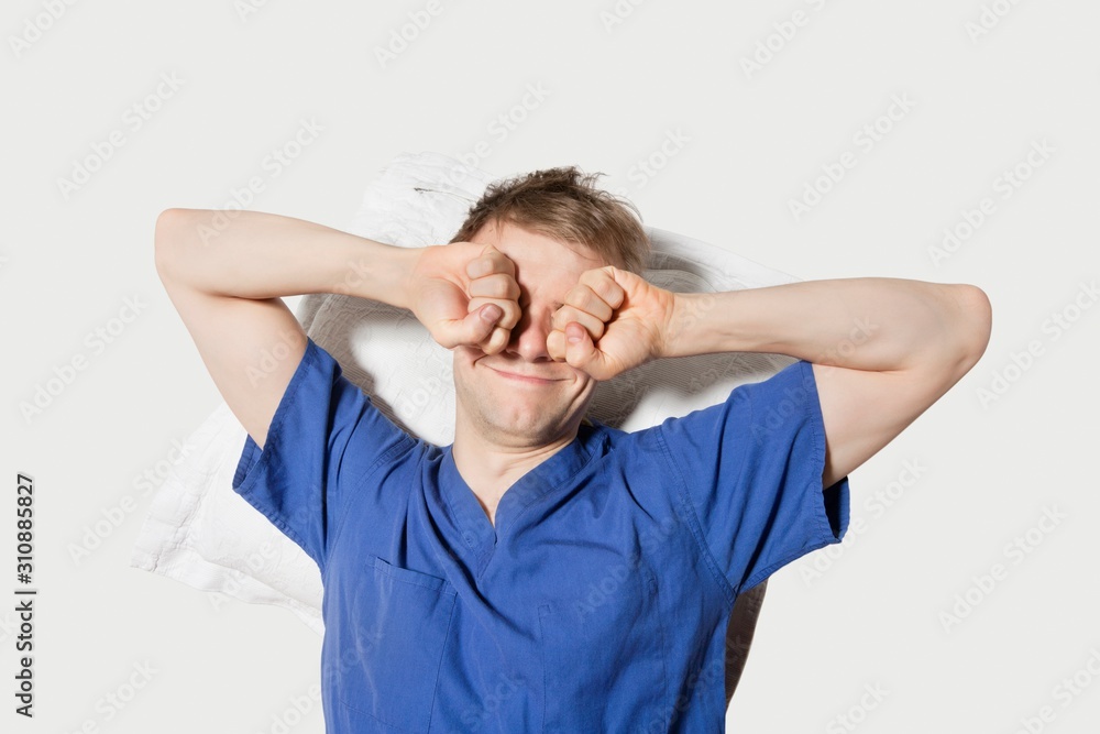 Young man rubbing eyes while waking up over colored background Young man rubbing eyes while waking up over colored background