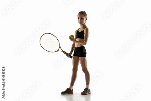 Little caucasian girl playing tennis on white studio background. Cute model training, practicing in motion, action. Youth, flexibility, power and energy. Movement, ad, sport, healthy lifestyle concept