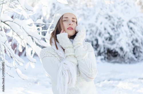 Portrait of young beautiful woman in white warm sweater and hat enjoying the winter time. © Ant