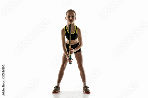 Little caucasian girl playing tennis on white studio background. Cute model training  practicing in motion  action. Youth  flexibility  power and energy. Movement  ad  sport  healthy lifestyle concept