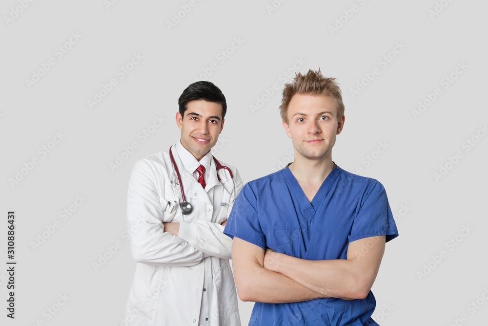 Portrait of male nurse and doctor standing with arms crossed over gray background Portrait of male nurse and doctor standing with arms crossed over gray background