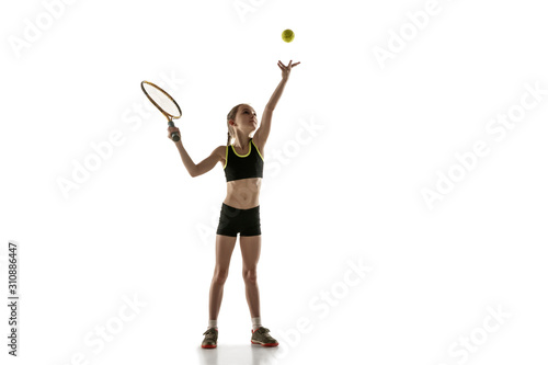 Little caucasian girl playing tennis on white studio background. Cute model training, practicing in motion, action. Youth, flexibility, power and energy. Movement, ad, sport, healthy lifestyle concept
