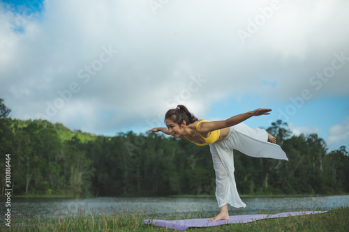 Asian woman with practicing yoga posture on the mountain at sunset. wellness and wellbeing concept.
