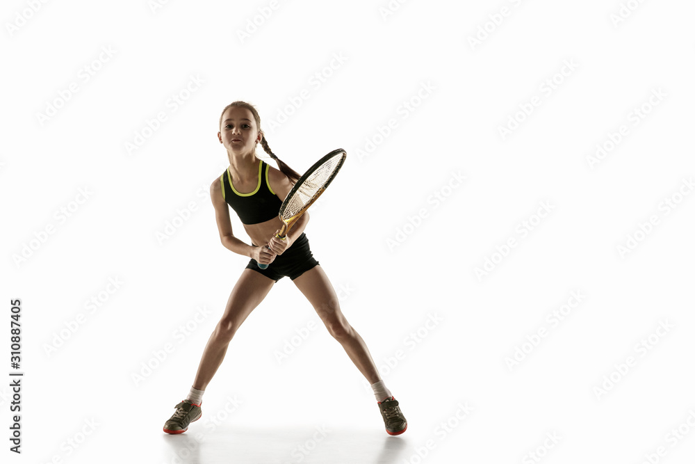 Little caucasian girl playing tennis on white studio background. Cute model training, practicing in motion, action. Youth, flexibility, power and energy. Movement, ad, sport, healthy lifestyle concept Little caucasian girl playing tennis on white studio background. Cute model training, practicing in motion, action. Youth, flexibility, power and energy. Movement, ad, sport, healthy lifestyle concept