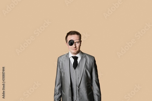 Foto Portrait of a young businessman with eye patch over colored background