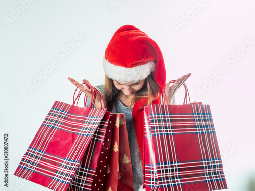 Young pretty woman in santa hat holding christmas bags
