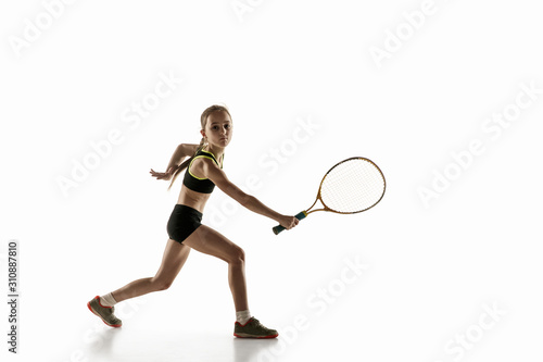 Little caucasian girl playing tennis on white studio background. Cute model training, practicing in motion, action. Youth, flexibility, power and energy. Movement, ad, sport, healthy lifestyle concept © master1305