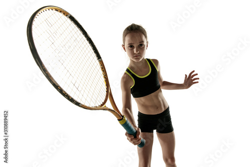 Little caucasian girl playing tennis on white studio background. Cute model posing confident and calm in motion, action. Youth, flexibility, power and energy. Ad, sport, healthy lifestyle concept.