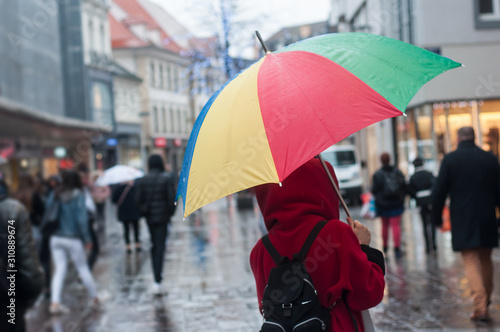 Portrait on back view of woman walking in the street with rainbow umbrella