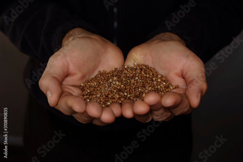 buckwheat in hands on black background