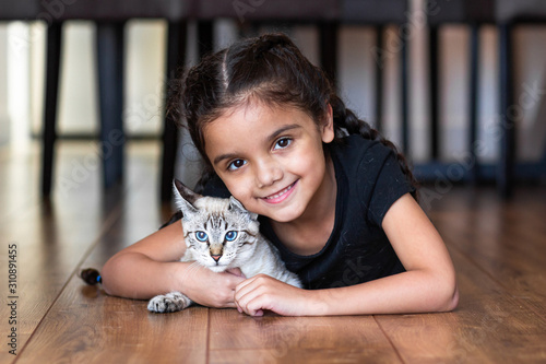 Sweet and Happy little girl child with her kitten cat on the floor in the house.  Brunette and brazilian. (ID: 310891455)