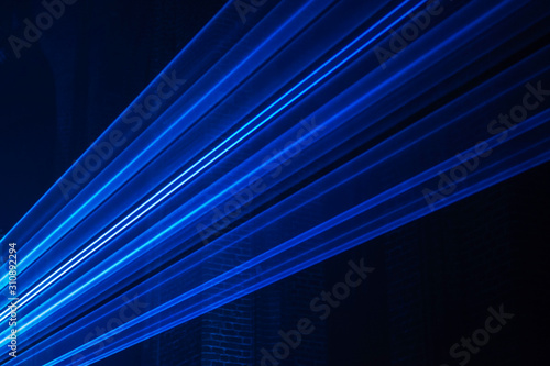 Abstract background with blurred ray of light. Lighting and spotlights lines, stage light and smoke. Disco laser with beams through smoke. Classic blue, trend color. Color of the year