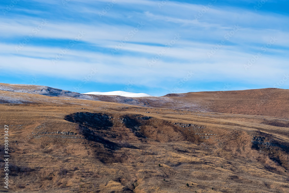 Landscape with dry ground and snow in North Caucasus mountains in autumn