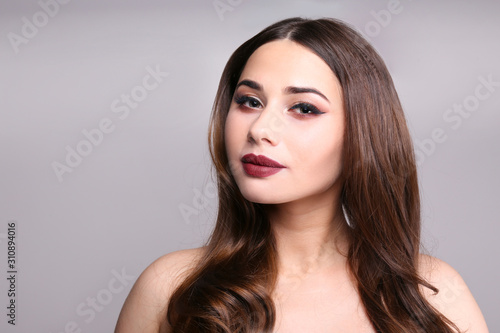 Portrait of young beautiful woman with perfectly clean face skin wearing professional make up. Female with long black hair. Close up, copy space background.