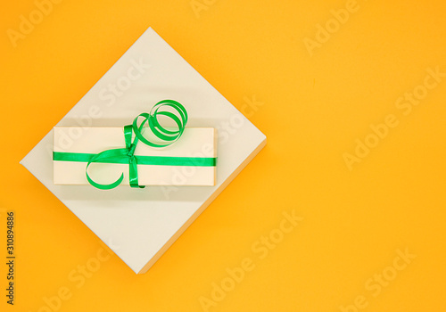 Photos Gift boxes with green ribbon on yellow background.