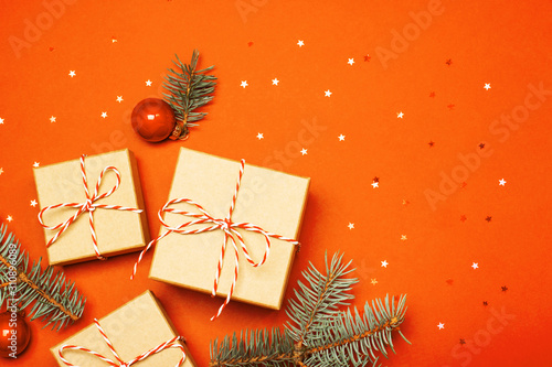 Christmas composition with gifts, branches and holiday elements on the orange background. Flat lay. Merry Christmas, New Year, winter concept.